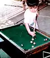 A child plays a miniature billiard table set on a coffee table and using small balls.