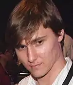 A man with brown hair looking below the camera.