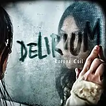 A dark haired woman (Cristina Scabbia) stares into a mirror covered in condensation, with the word "Delirium" drawn onto it by the woman.