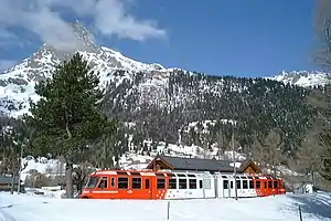 White-and-red train in snow before the mountains