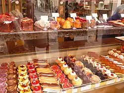 Shop display featuring multiple rows of small, colourful pastries.