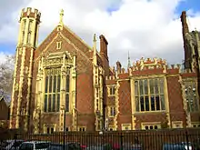 a pair of very old, red and white brick buildings. The one on the left is larger than that on the right and has a small tower. The buildings feature large stained glass windows on the front.