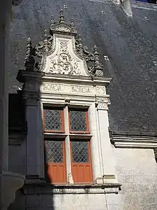 Window with a lucarne, raised above the roof and framed with sculpted pilasters,  characteristic of French Renaissance style