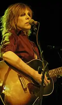 Singer Lucinda Williams strumming a guitar.