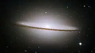 The dark band of the "dust lane" is clearly visible against the brighter background of stars within the Sombrero Galaxy.