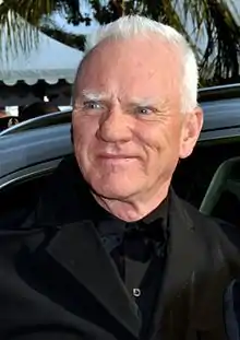 A blue-eyed, white-haired man of about 70, smiling