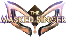 The words "The Masked Singer" in a gold-colored, capitalized typeface appearing in front of a 3D mask design