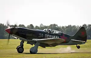 Side view of a MiG-3 painted in green and brown with the VVS insignia taking off. The slogan "Za Rodinu" (For [the] Motherland) is painted on its side.