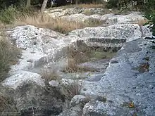 Ancient winepress in Israel with the pressing area in the center and the collection vat off to the bottom left.