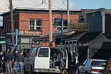 A film crew and van outside of a building with a sign that reads "Mr. Gold Pawnbroker & Antiquities Dealer"