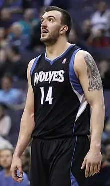 Nikola Peković, bearded, in a black Timberwolves jersey with blue and white trim