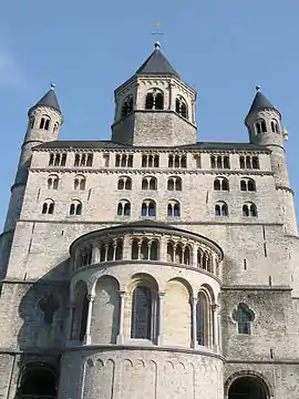 A tall rectangular structure of grey stone and stern appearance with a jutting apse and a small octagonal belfry.