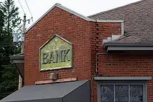 A portion of a brick building, with an aged sign saying "Bank".