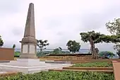 A photograph taken in 2014 of a large memorial within a school surrounded by trees.