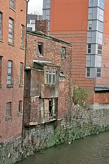 Image 3A 19th-century slum dwelling. The overhang contained privies, whose waste fell straight into the River Medlock below. (from History of Manchester)