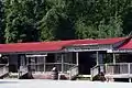 A historic market with red roof with a wooden "Ozark Folk Center" sign.