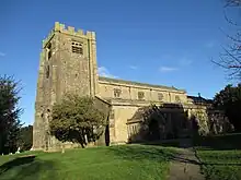 A stone church seen from the south-west with a large battlemented tower