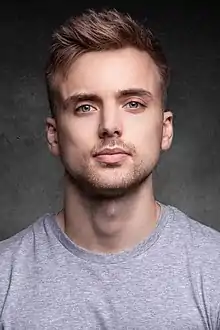 White man with light brown hair and a grey t-shirt