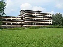 A low-rise office building with a lawn in front and a half-cloudy sky in the background