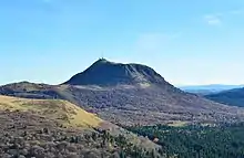 Distant view of a cratered cinder cone dormant volcano with a road winding to its summit