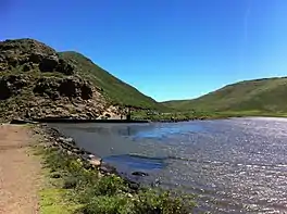 Lake and dam surrounded by green hills