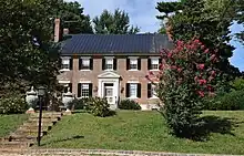 A photograph of a stately 18th century brick house with stone stairs leading up to it.