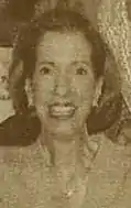 A sepia-colored newspaper photograph of a smiling white woman.