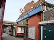 A brown-bricked building with a rectangular, dark blue sign reading "ROYAL OAK STATION" in white letters all under a light blue sky