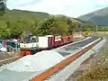 Northerly view of Rhyd Ddu station in the final stages of construction on 26 May 2003. Diesel loco Conway Castle hauls a PW train with a tamping machine in the background.