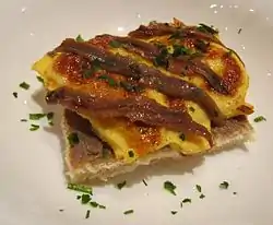 Scotch woodcock garnished with anchovy fillets and parsley. The anchovy paste is beneath the anchovy fillets.