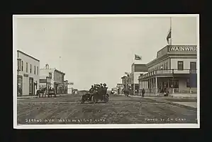 Second Ave. with a focus on a group of people in a motor car in the middle of the street in front of the Wainwright Hotel