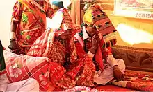 A festively-dressed couple sits cross-legged on the floor