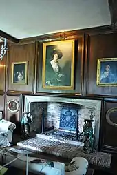 portrait of woman hanging above a fireplace in a wood-panelled room