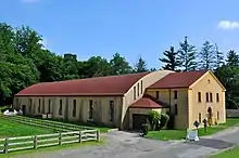 A two-story tan building with a red half-barrel roof