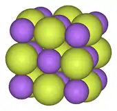 Checkerboard-like lattice of small blue and large yellow balls, going in three dimensions so that each ball has 6 nearest neighbors of opposite type