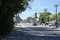 A four-lane divided street, with vehicles travelling in both directions and construction apparatus in the distance.