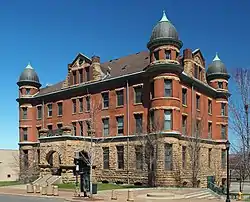 A three-story building with round corner towers and a projecting stone entry