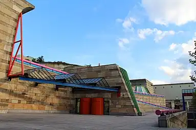 Contradiction (in this case, the mix between monumental curving forms, columns, bossages, but also other Classical elements, and High-Tech glazing, with highly saturated colours) - Neue Staatsgalerie, Stuttgart, Germany, by James Stirling (1984)