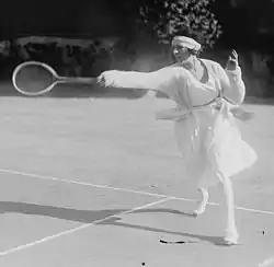 Lenglen hitting a forehand near the baseline in the doubles alley