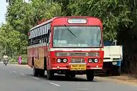 A bus in a road with trees in the background