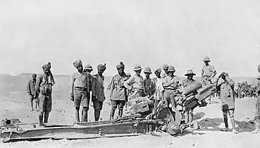 British and Indian troops examining a wrecked Turkish artillery gun.