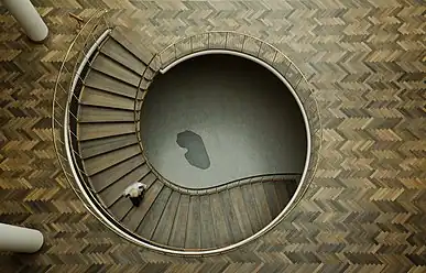 A staircase in Aarhus City Hall, Denmark. The dark grey, kidney-shaped capstone seen at the bottom of the stairwell contains the three foundation stones of the building and was used as the reference point for height adjustment during the entire building period.