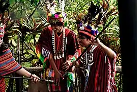 A local lets tourists try on their traditional attire.