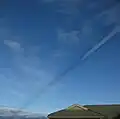 Shadow cast by vapor trail of passing aircraft