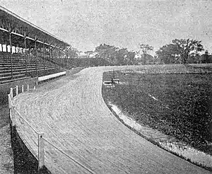 Photo of a covered wooden grandstand beside an oval track of dirt