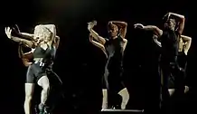 Madonna dancing with a group of dancers wearing black outfits