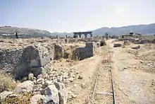 View of an old narrow-gauge railway track running into an excavated area alongside walls and foundations