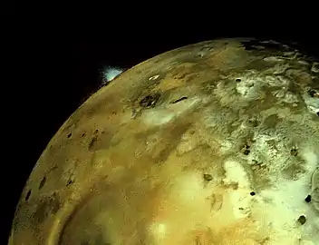 A volcanic eruption plume rises over the limb of Io