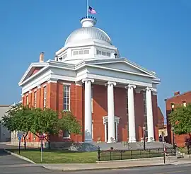 A brick building with four white columns in front and a silvery dome on top