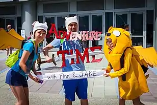 A sandwichboard with a drawing of Finn and Jake, and the caption "Every Adventure Begins With THINK"